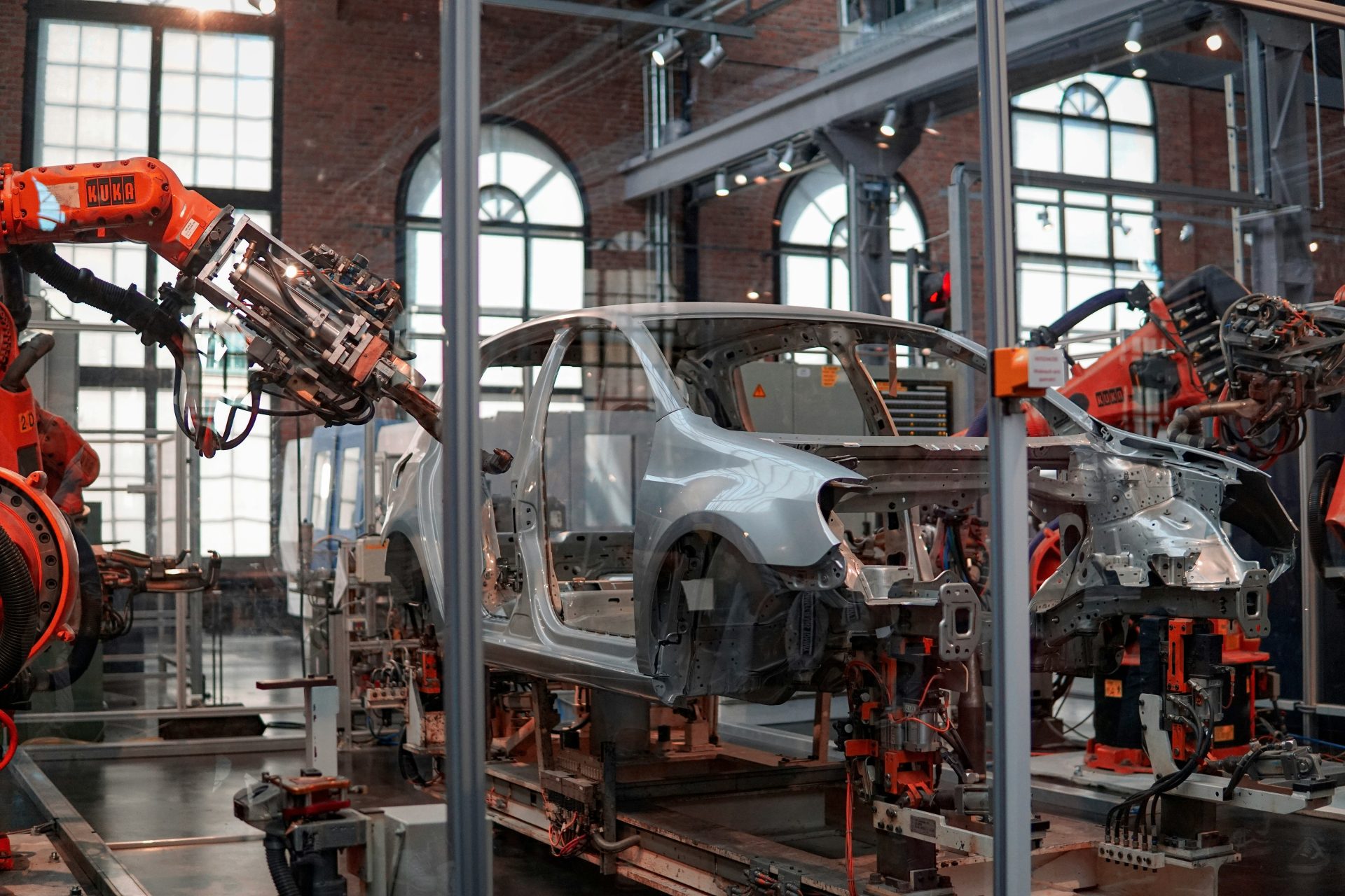 Das graue Fahrzeug wird in der Fabrik mithilfe von Robotern repariert.